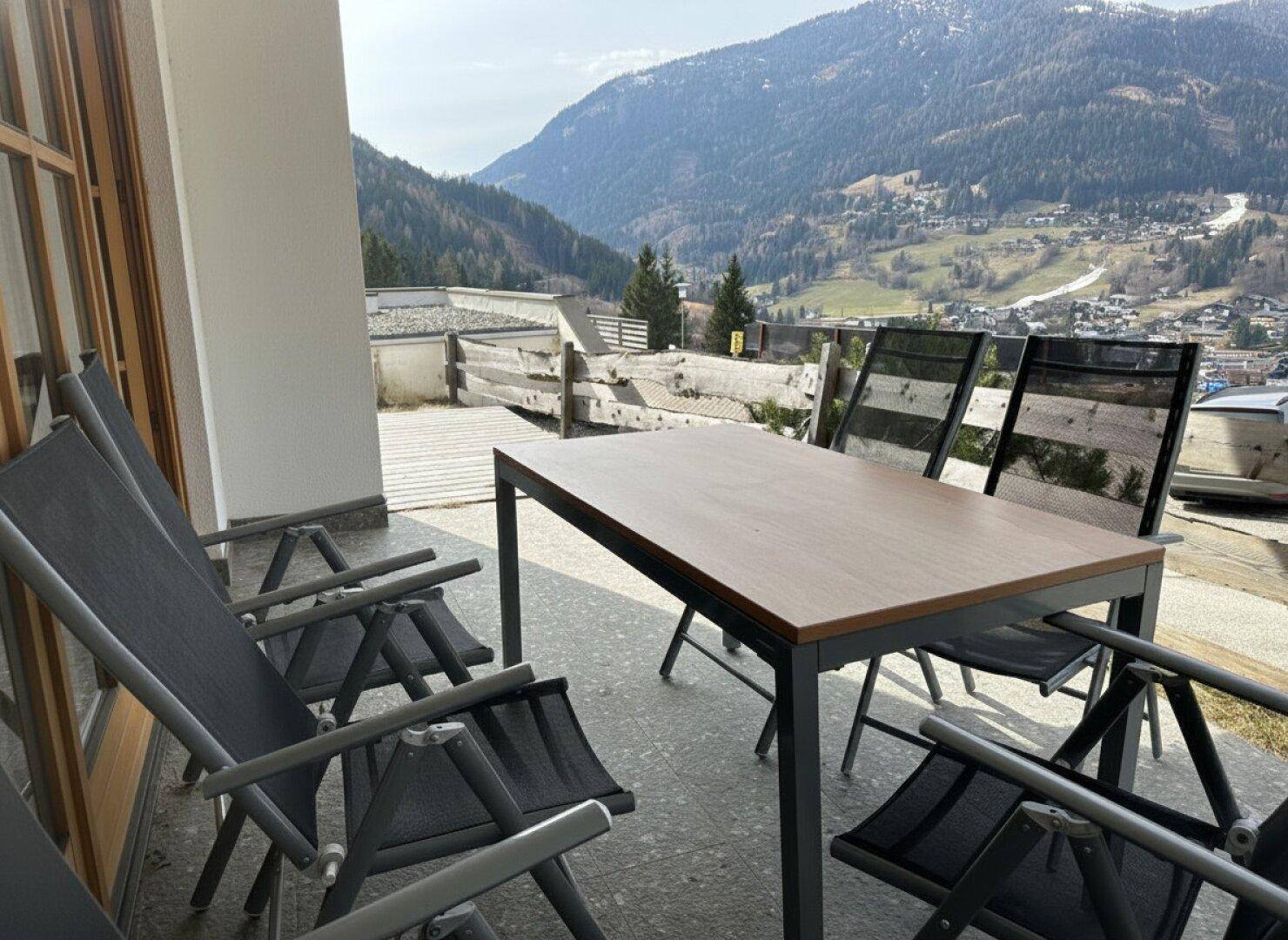 Möblierter Balkon mit Esstisch und Stühlen, ideal für Mahlzeiten mit Bergblick.