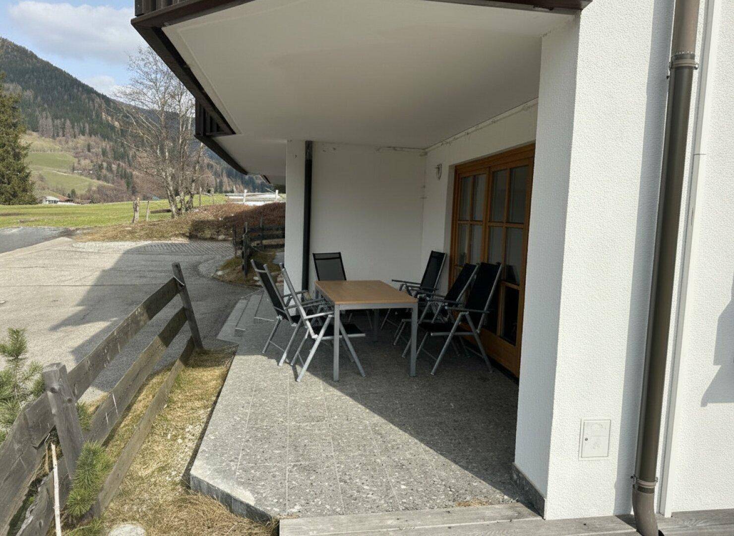 Überdachte Terrasse mit Sitzgelegenheiten und Blick auf die umliegende Natur.