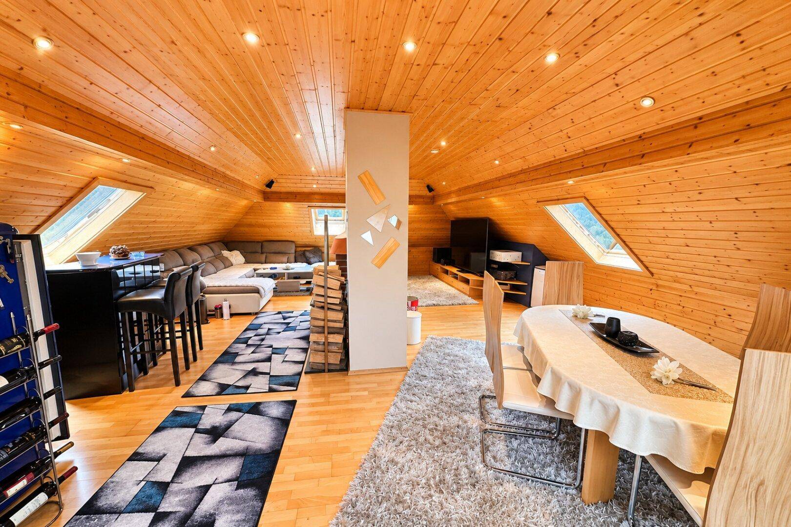 Heller Wohn- und Essbereich im Dachgeschoss mit Holzboden und Dachfenstern.