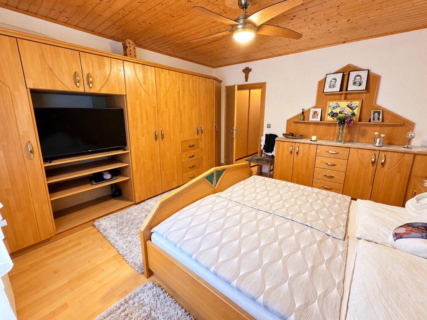 Geräumiges Schlafzimmer mit Holzboden, Einbauschränken und Holzdecke.