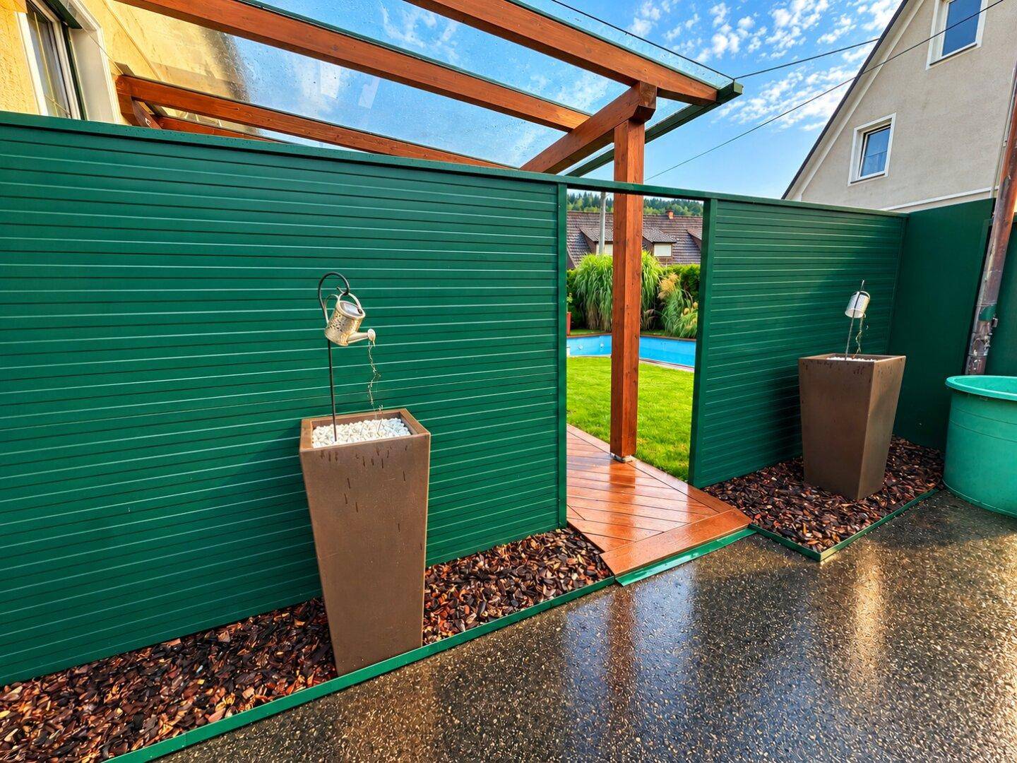 Eingang zum Gartenbereich mit Pool, umgeben von einer grünen Hecke.