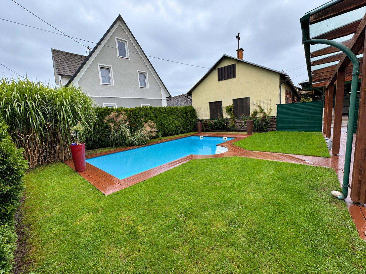 Gepflegter Garten mit Pool, Rasenfläche und umgebender Hecke.