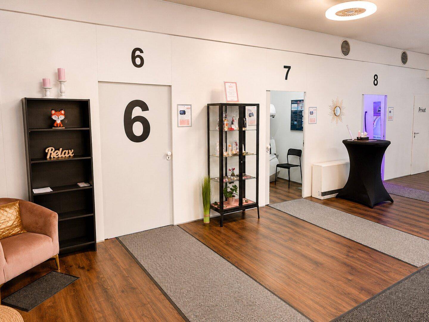 Flur mit einer Sitzecke, einem Regal und Zugängen zu den Kabinen 6, 7 und 8.