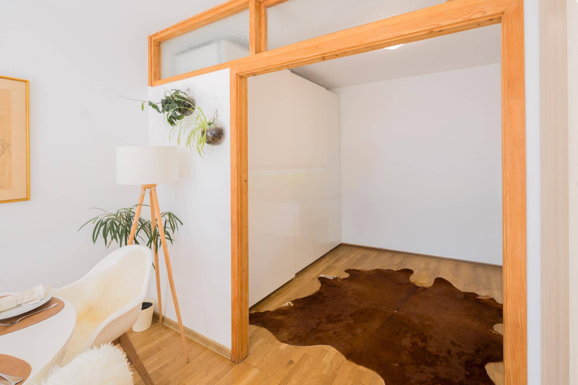 Heller Raum mit Holzboden und dekorativem Kuhfellteppich, verbunden mit dem Wohnbereich.