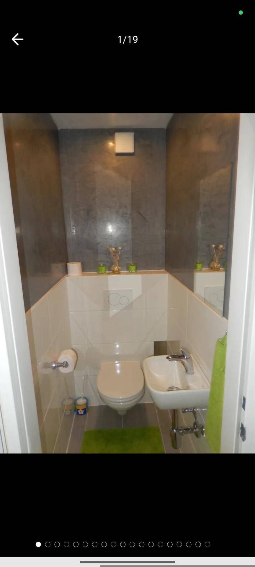 Modernes Gäste-WC mit wandhängender Toilette und kleinem Waschbecken in Grau und Weiß.