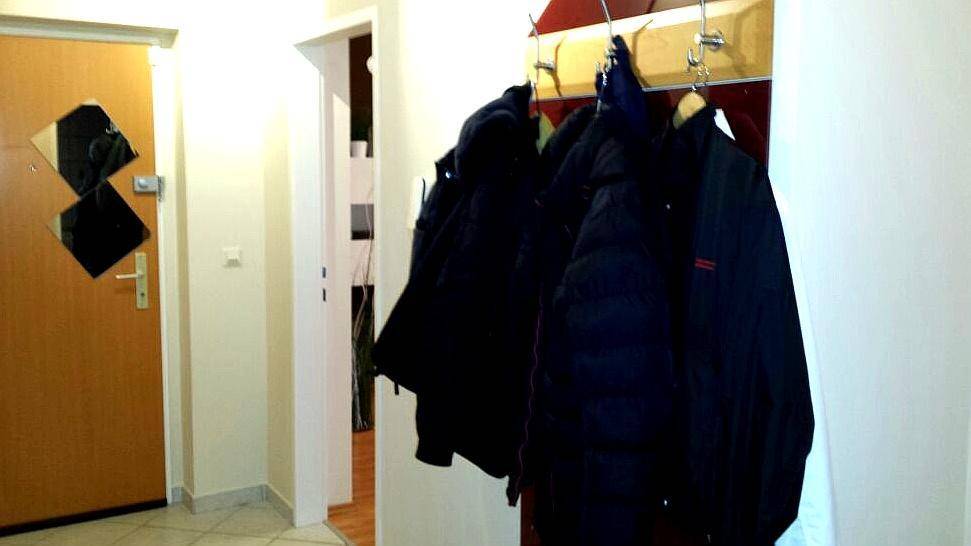 Eingangsbereich mit Garderobe und Holztür, der zu weiteren Räumen führt.