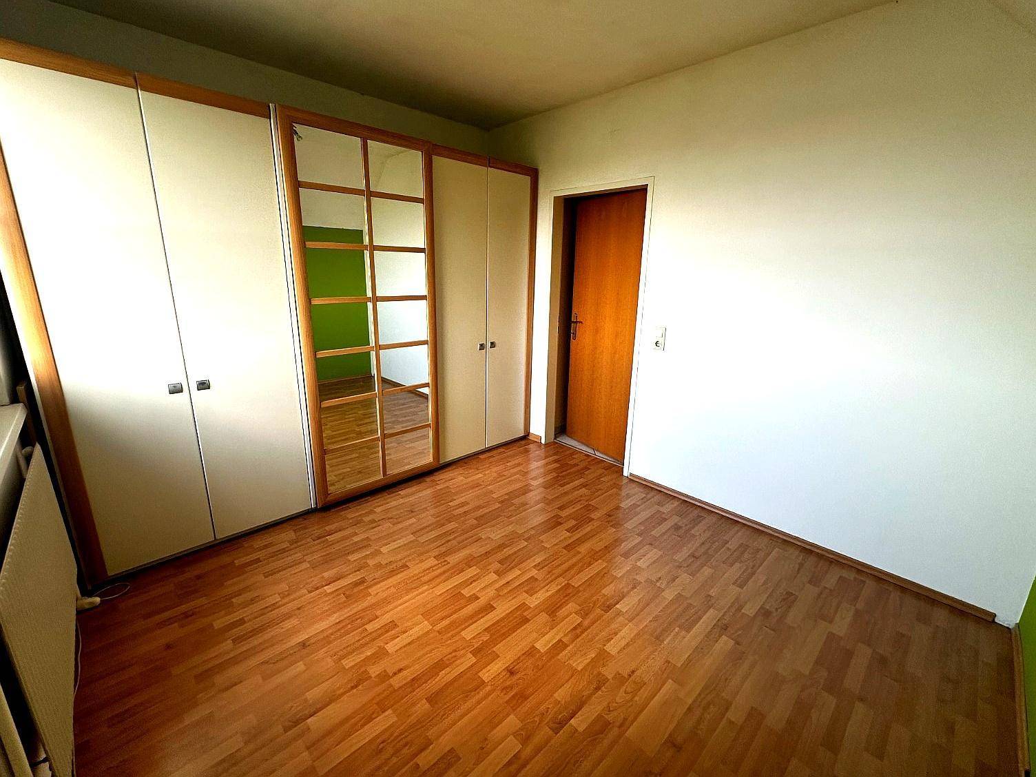 Schlafzimmer mit Einbauschränken, Spiegeltüren und hellem Holzfußboden.