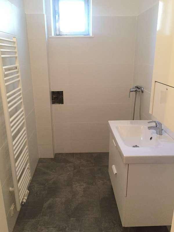 Modernes Badezimmer mit weißen Wandfliesen, Waschtisch, beheiztem Handtuchhalter und Fenster.