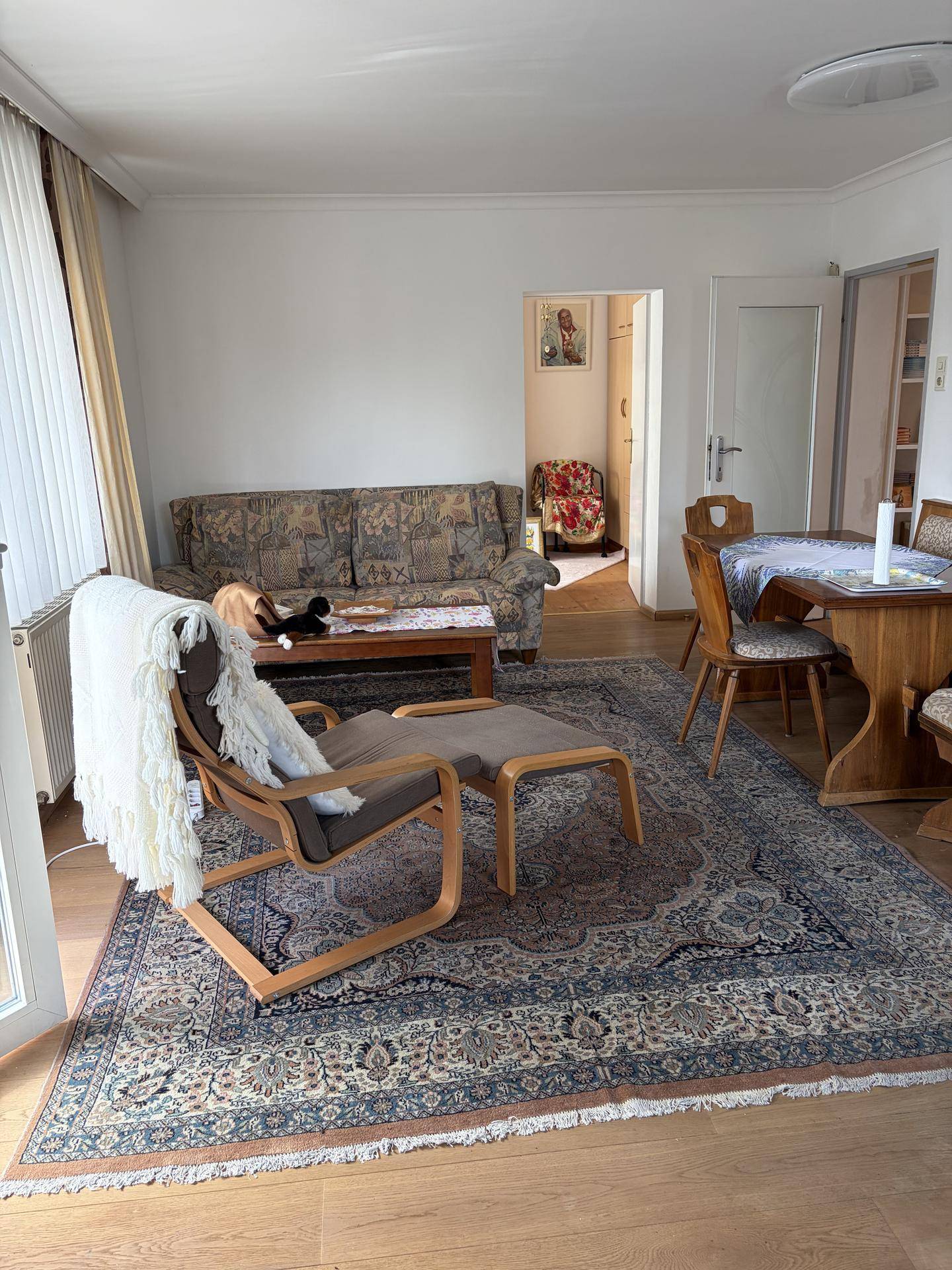 Geräumiger Wohn- und Essbereich mit Sofa, Sessel und traditionellem Teppich.