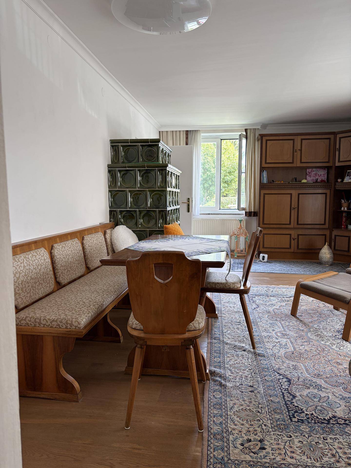 Gemütlicher Essbereich mit Holztisch, Eckbank und traditionellem Kachelofen.