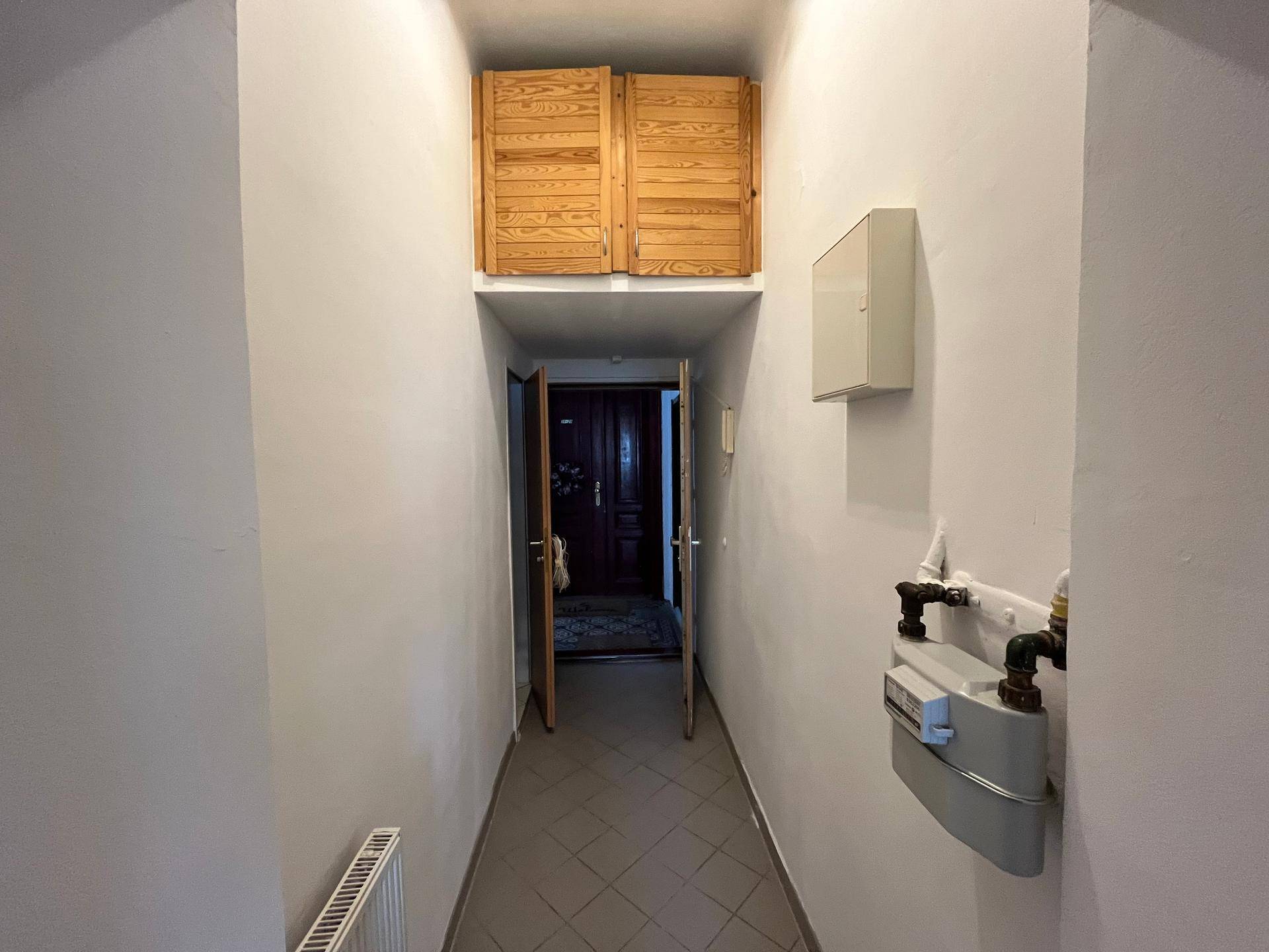 Eingangsbereich mit Fliesenboden und Blick auf die Wohnungstür am Ende des Flurs.