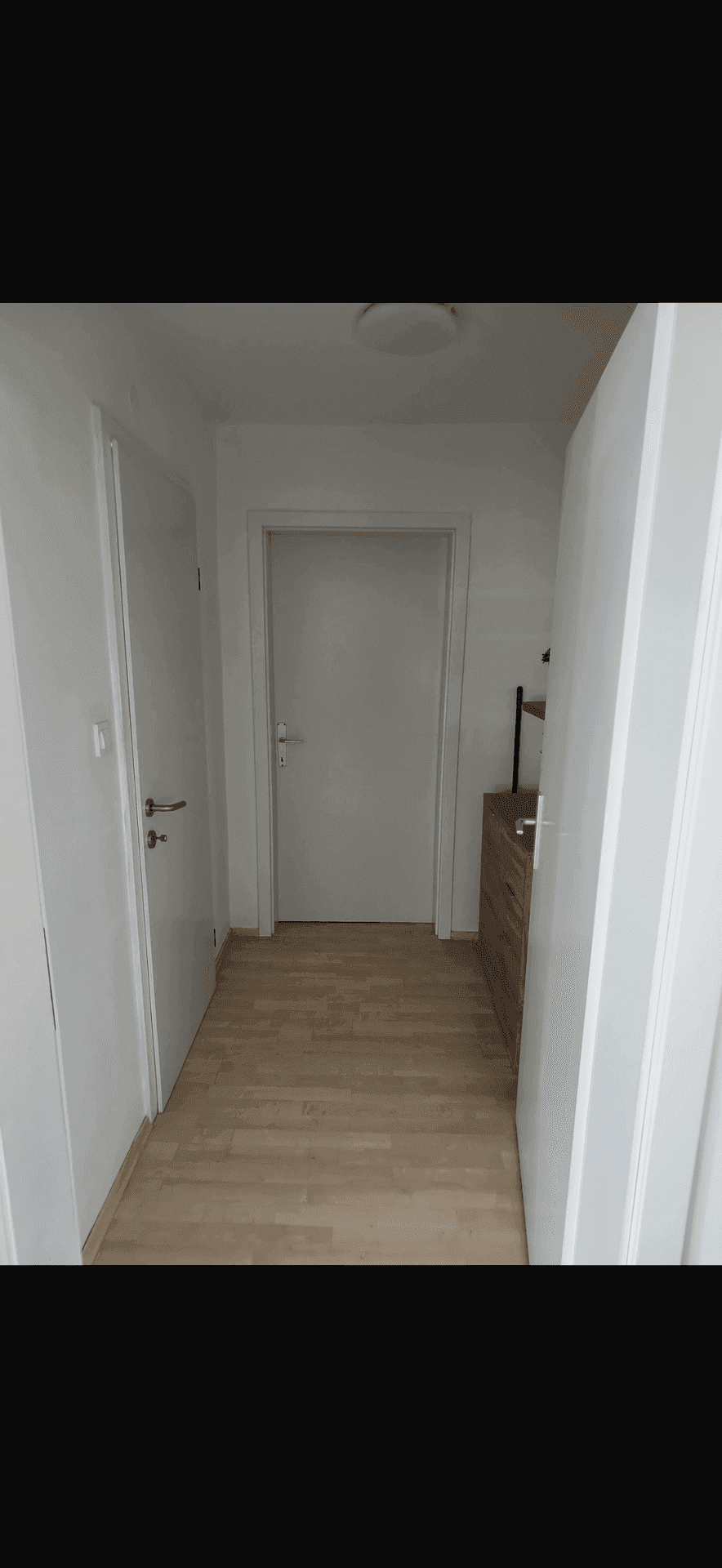 Heller Flur mit Laminatboden und weißen Türen, der zu verschiedenen Räumen der Wohnung führt.