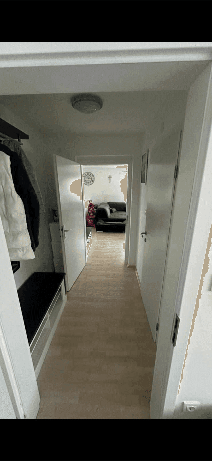 Flur mit Garderobe und Sitzbank, der zu einem hellen Wohnbereich der Wohnung führt.
