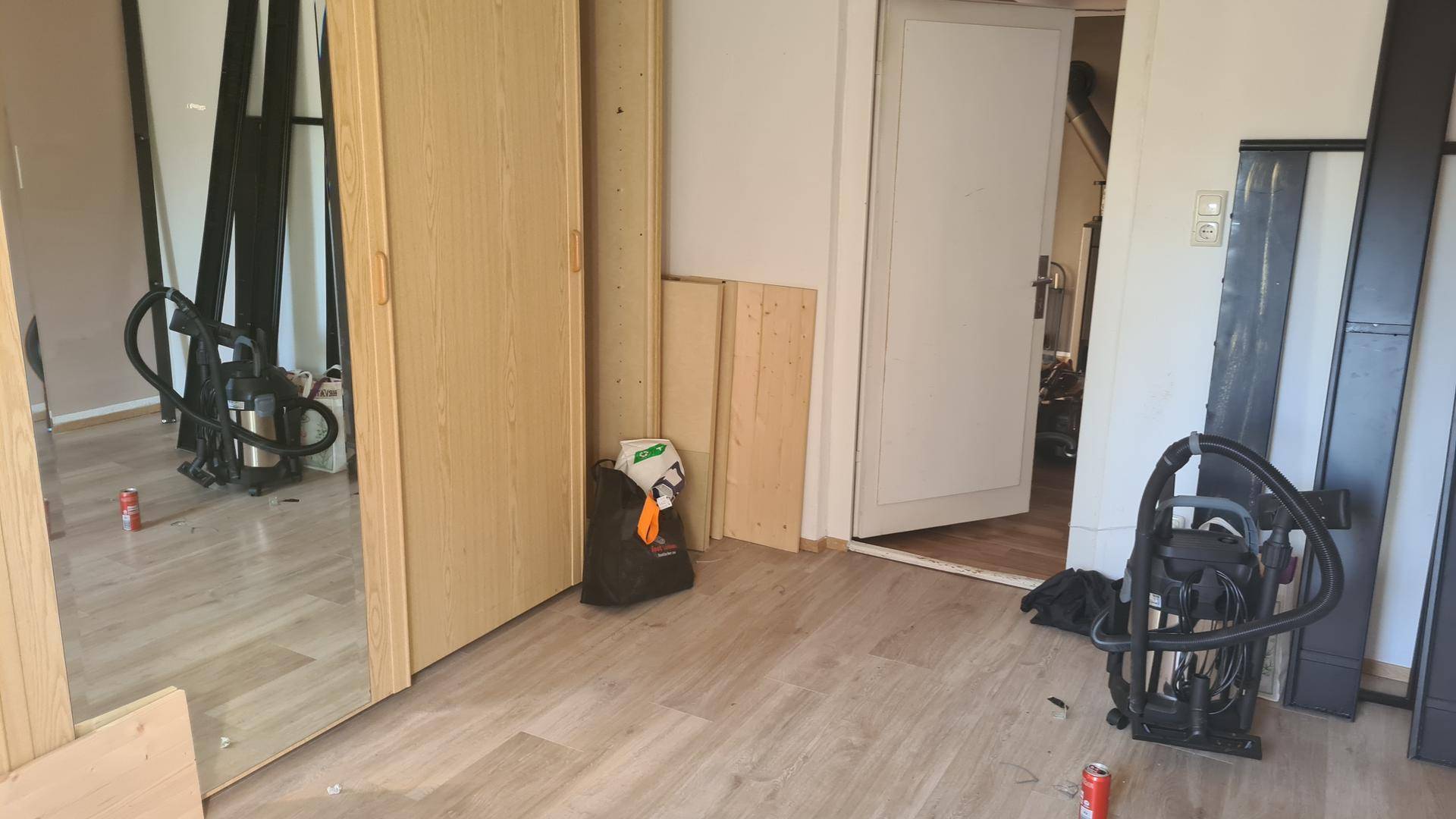 Innenraum mit Holzboden, Spiegelschrank und offener Tür.