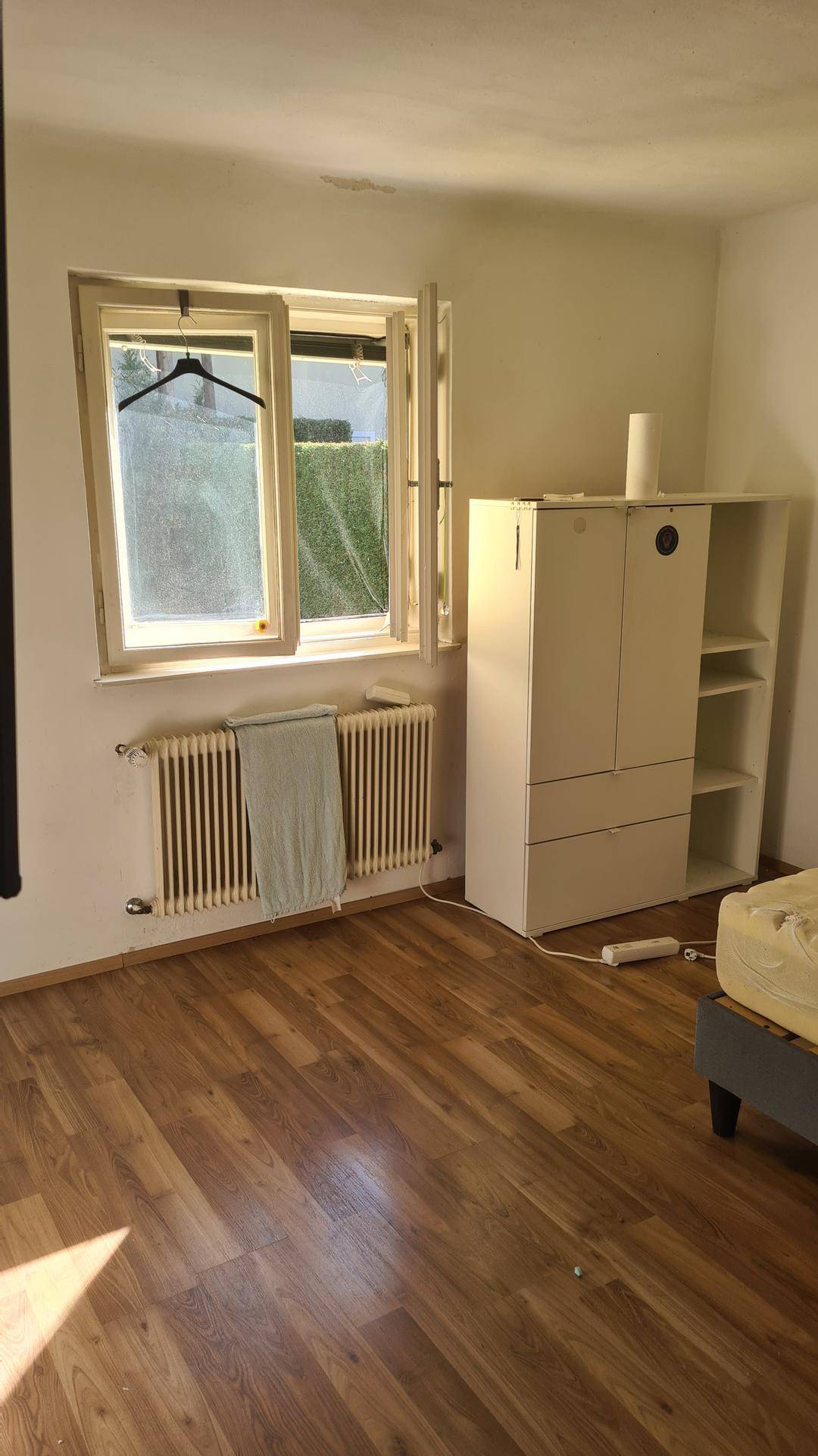Fensterbereich in einem Schlafzimmer mit Heizkörper und Holzboden.