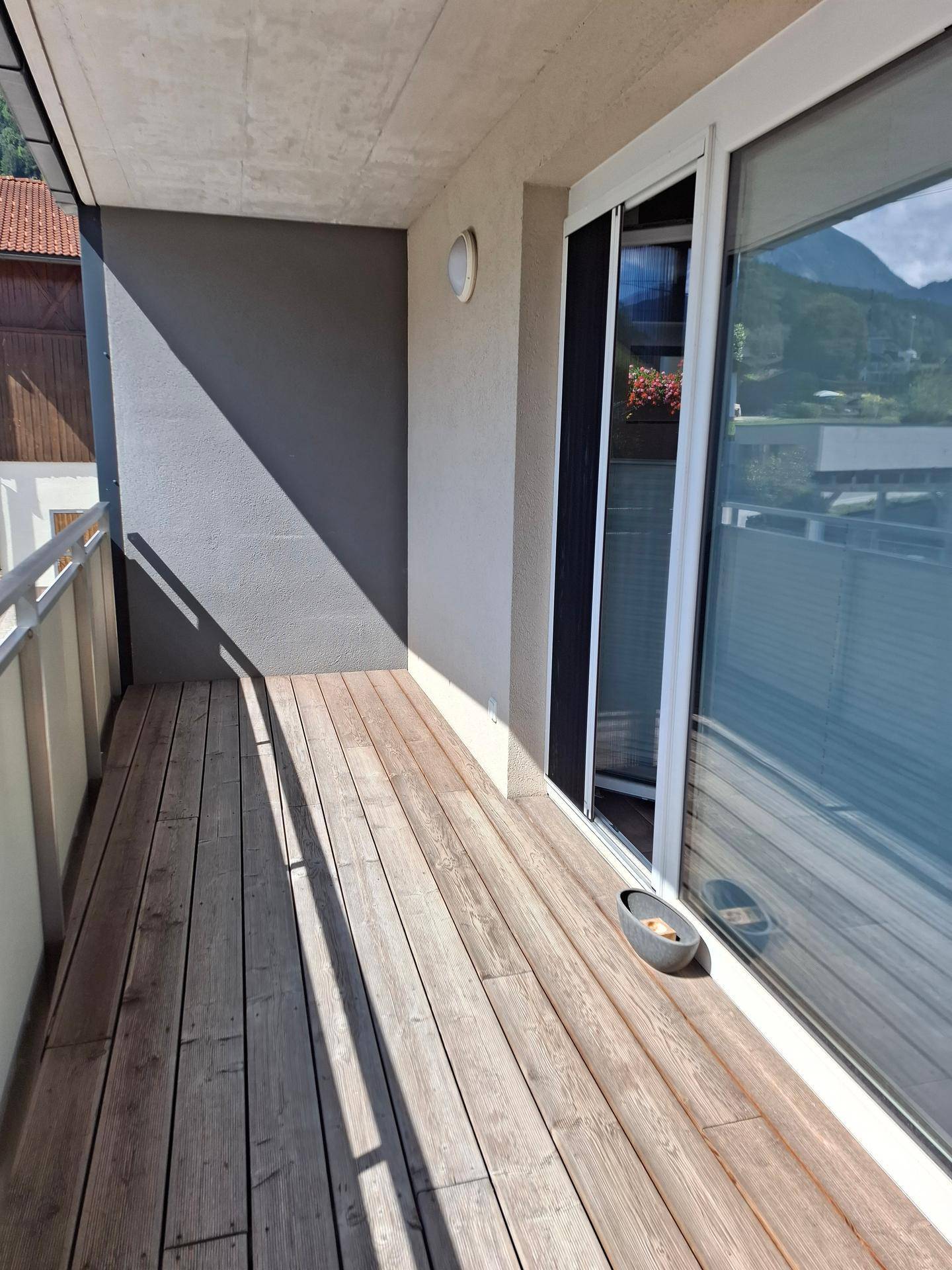 Geräumiger Balkon mit Holzboden und Blick auf die umliegende Berglandschaft.