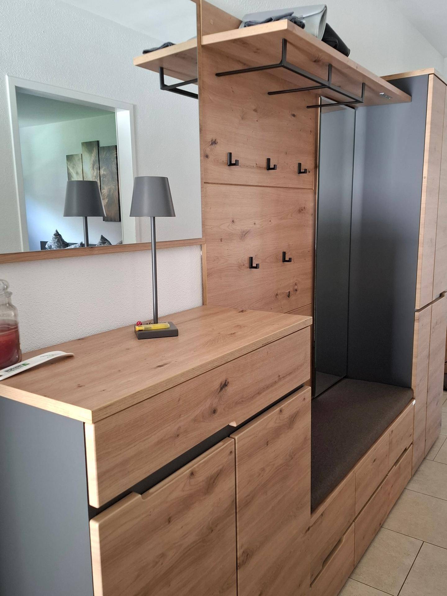 Heller Eingangsbereich mit moderner Garderobe aus Holz und integrierter Sitzbank.