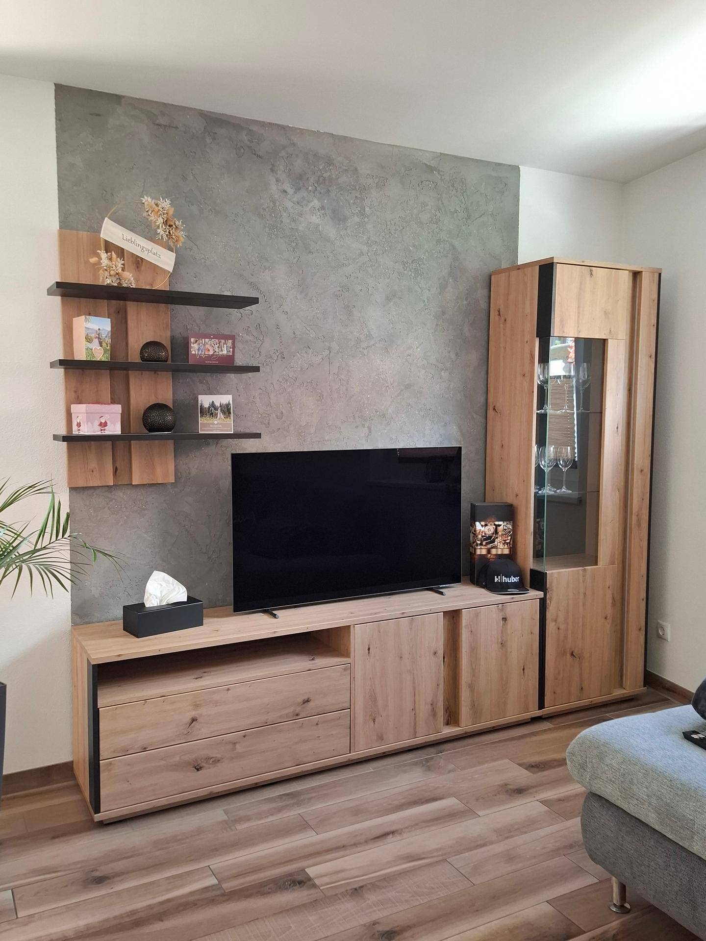 Moderner Wohnbereich mit TV-Möbeln aus Holz und einer strukturierten Wandgestaltung.