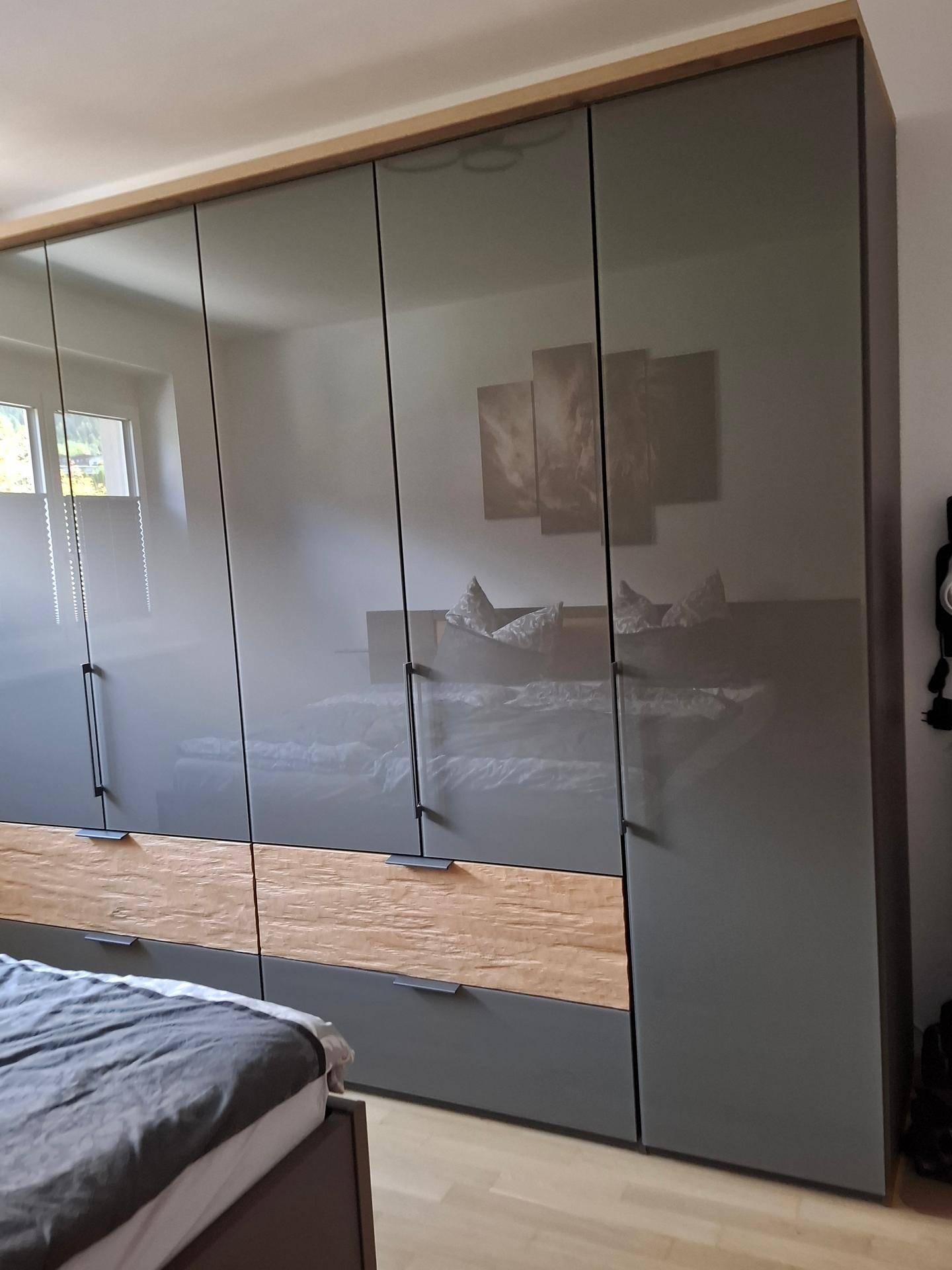 Schlafzimmer mit großem, modernem Kleiderschrank in Grau und Holzakzenten.