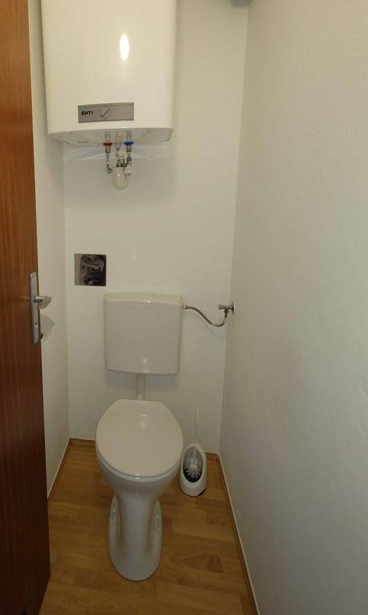 Separates WC mit Toilette und einem darüber installierten Warmwasserbereiter.