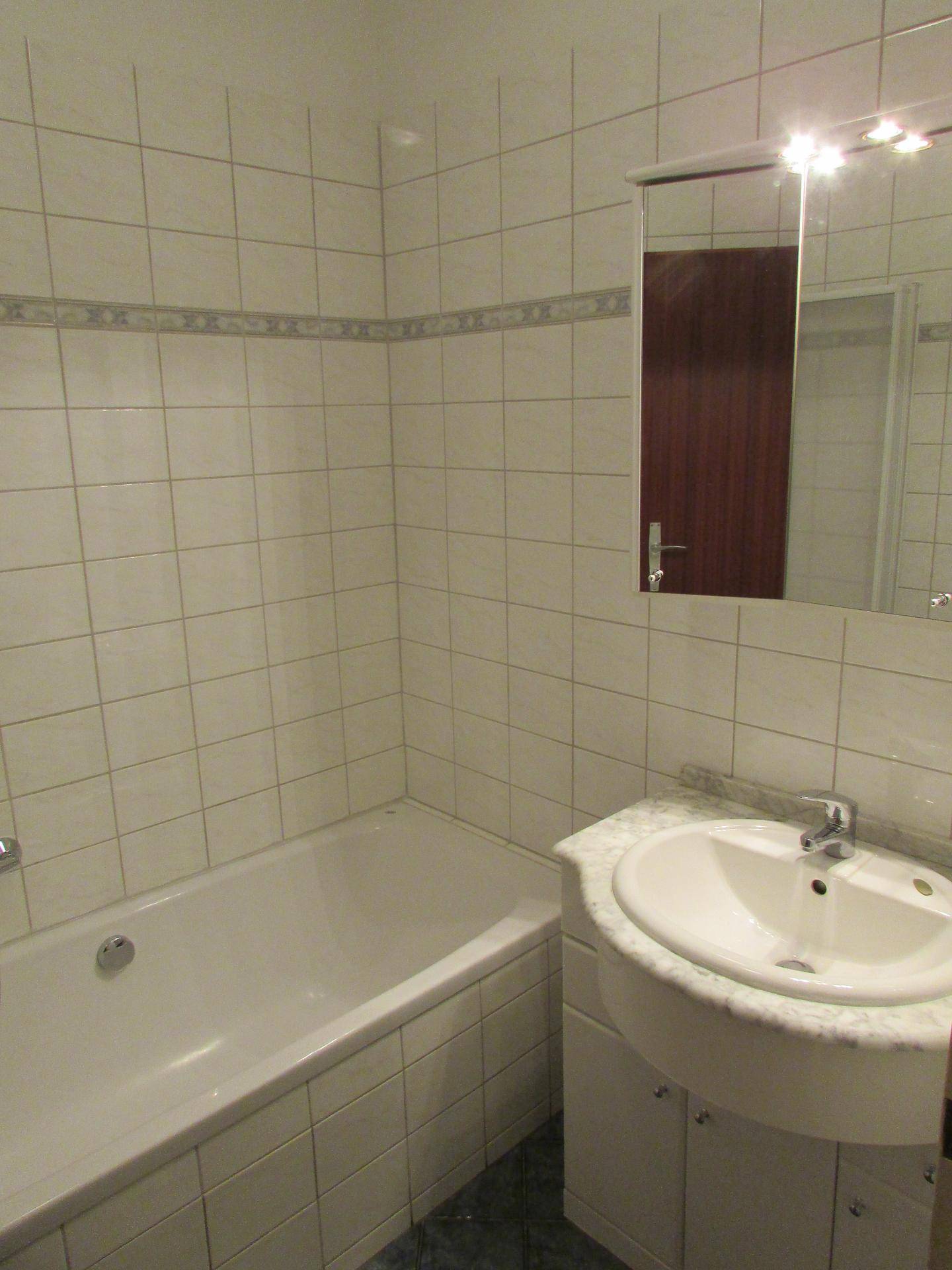 Gefliestes Badezimmer mit Badewanne, Einzelwaschbecken und Spiegelschrank.