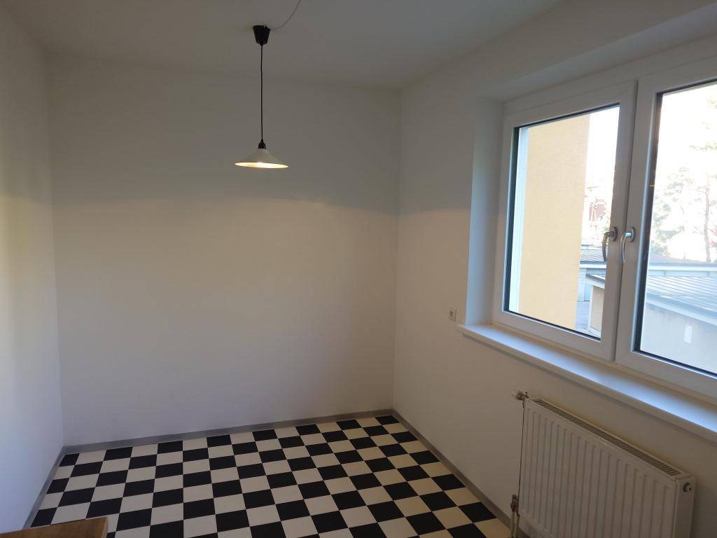 Heller Raum mit schwarz-weißem Fliesenboden und großem Fenster, ideal als Essbereich nutzbar.