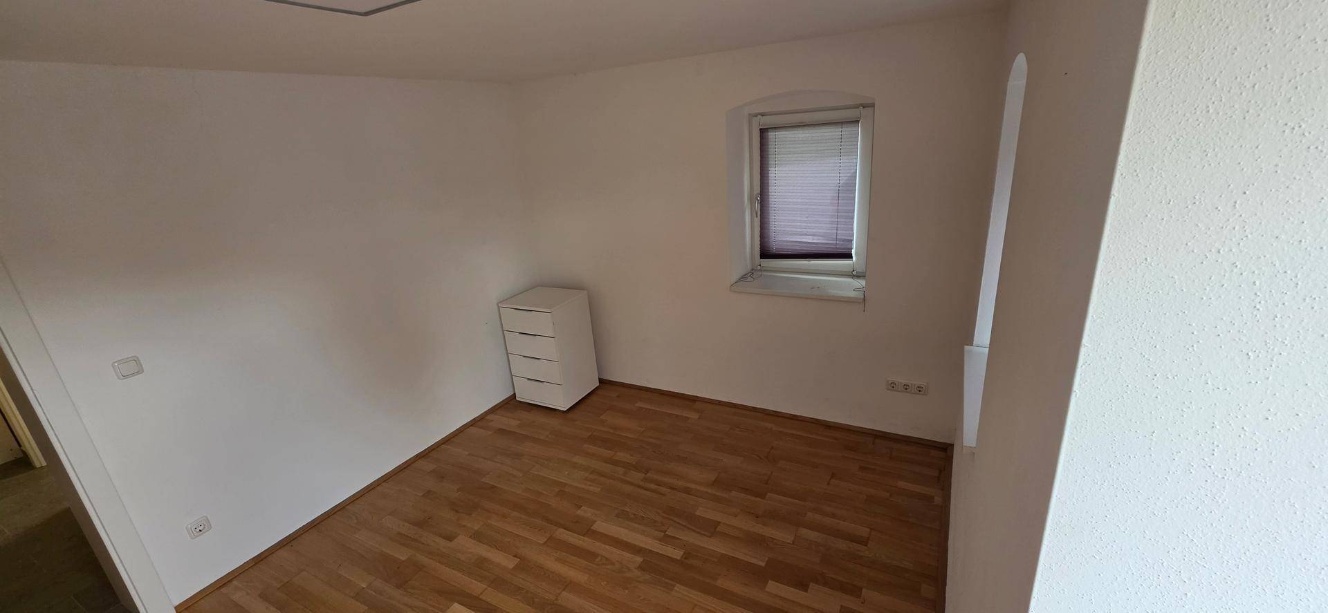 Ruhiges Schlafzimmer mit Holzboden und einem Fenster, ideal für erholsame Nächte.