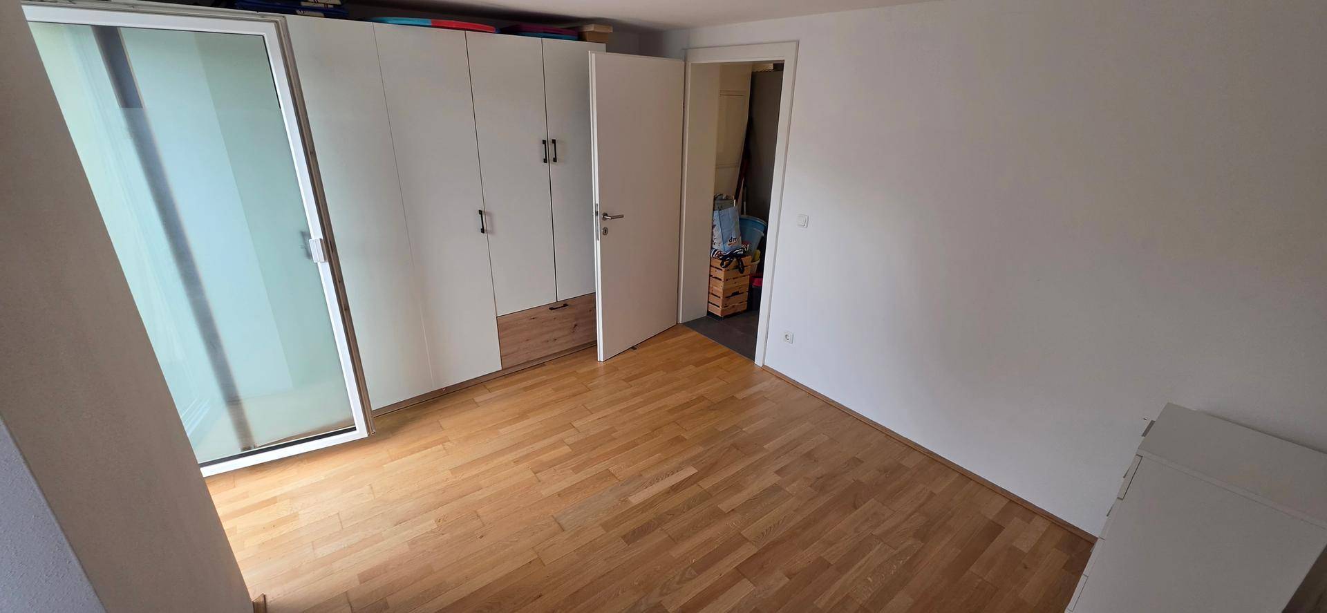 Geräumiges Schlafzimmer mit Holzboden und großem Einbauschrank für viel Stauraum.