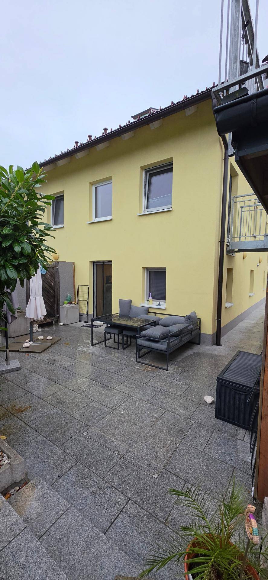 Gepflasterte Terrasse mit modernen Gartenmöbeln und Zugang zum Haus.