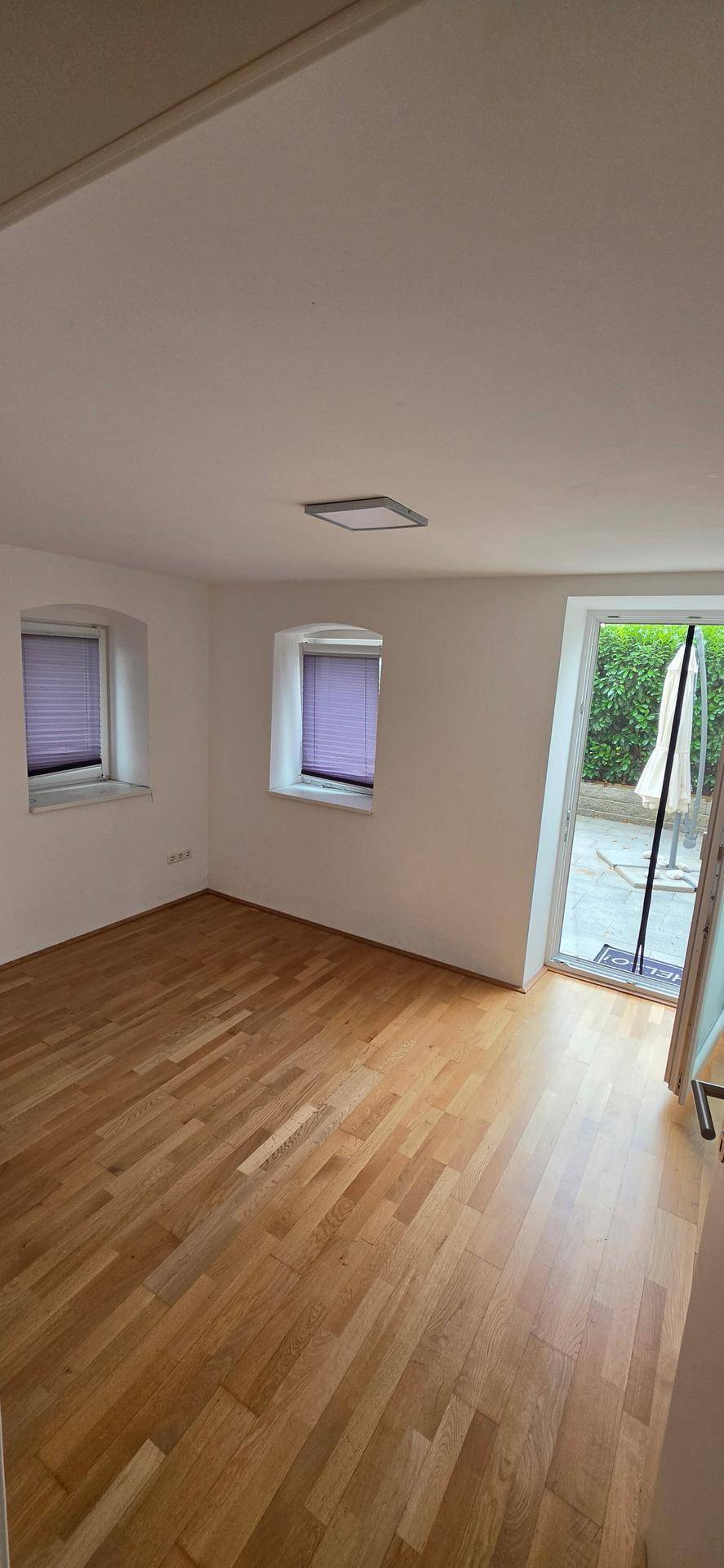 Helles Schlafzimmer mit Holzboden und direktem Zugang zu einem Außenbereich.