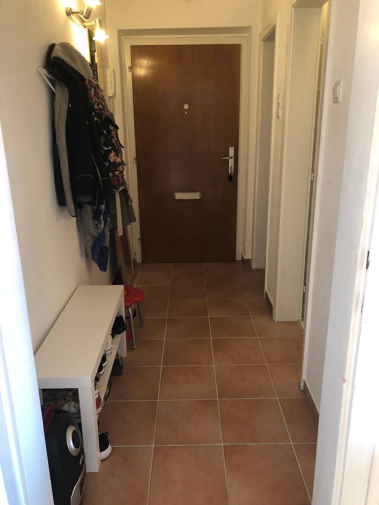 Eingangsbereich mit Fliesenboden, Garderobe und dunkler Eingangstür.