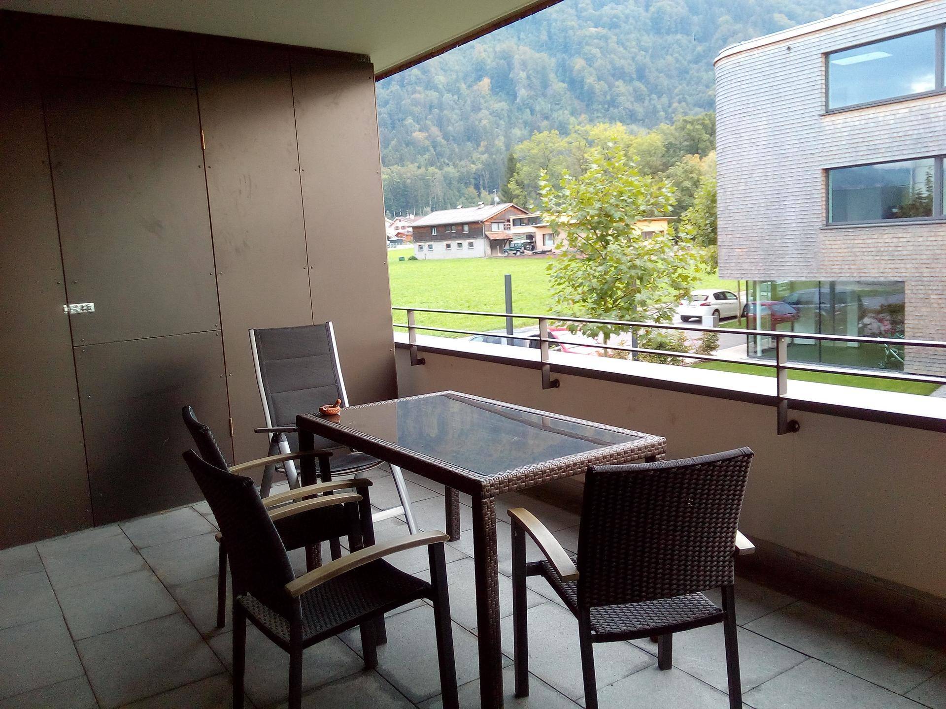 Geräumiger Balkon mit Esstisch und Stühlen, bietet einen schönen Blick auf die grüne Landschaft.