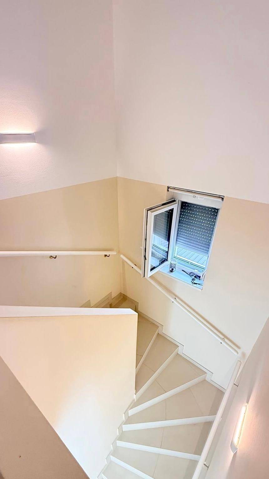 Treppenhaus mit einem Fenster, das mit einem Rollladen ausgestattet ist.