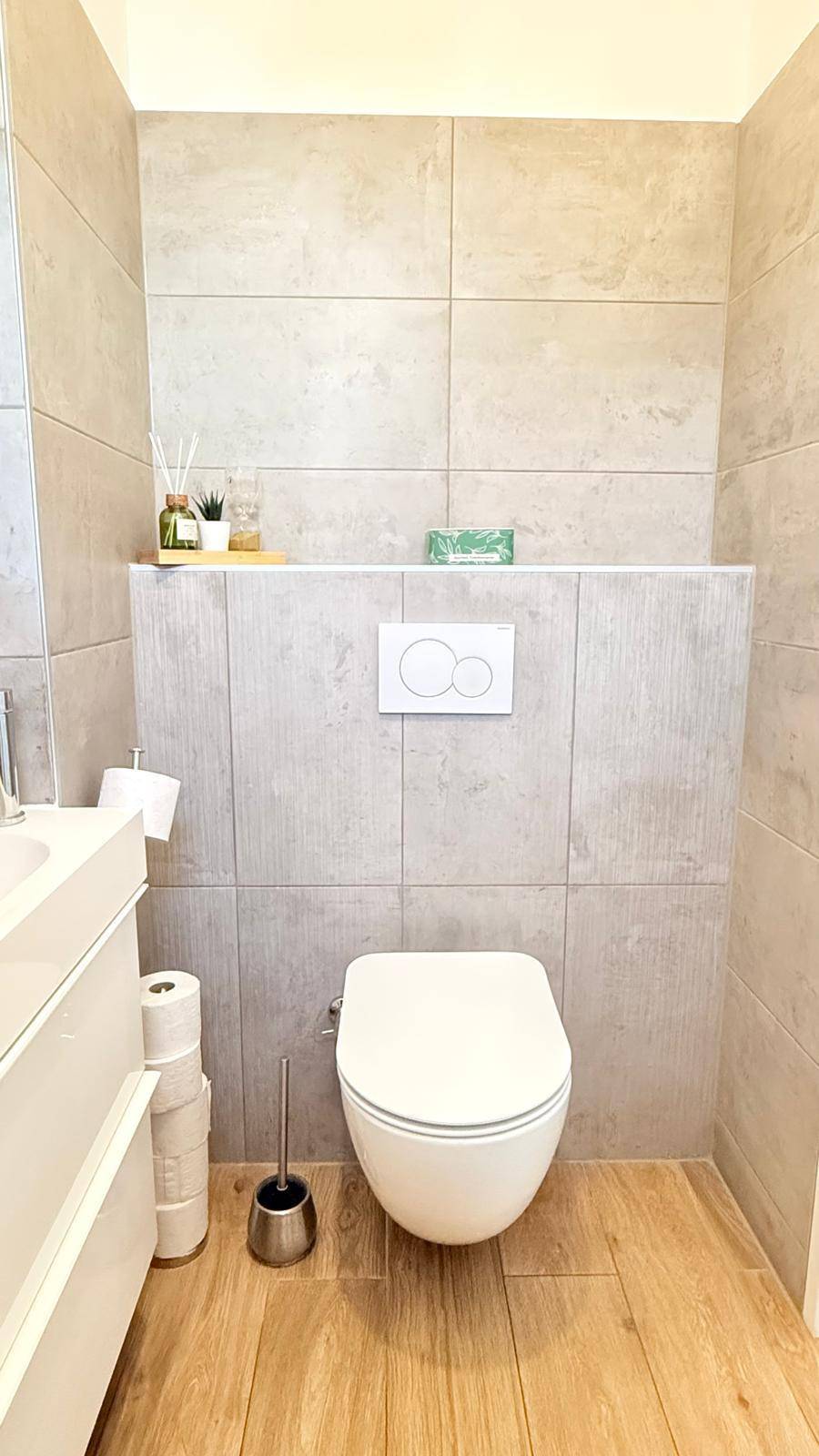 Gäste-WC mit wandhängender Toilette und modernen Fliesen an den Wänden.