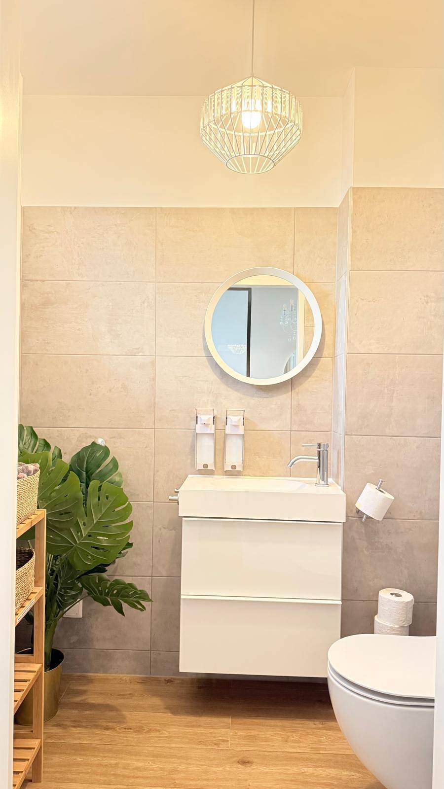 Modernes Gäste-WC mit wandhängendem Waschbecken und WC, sowie Fliesen an den Wänden.