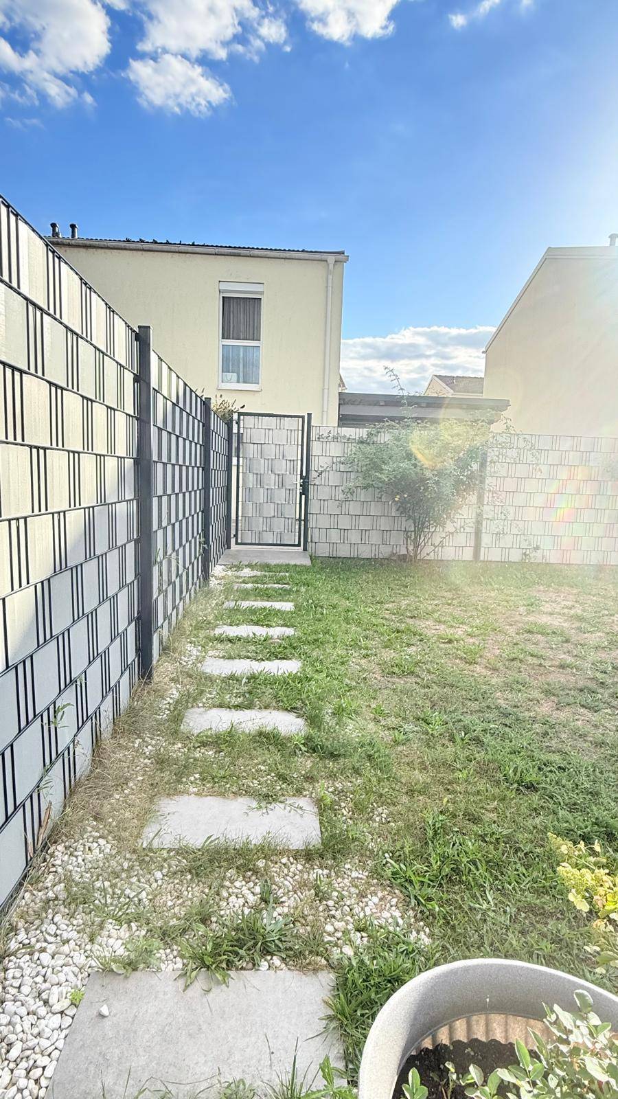 Gartenweg mit Trittsteinen, umzäunt von einem modernen Zaun und einem Gartentor.