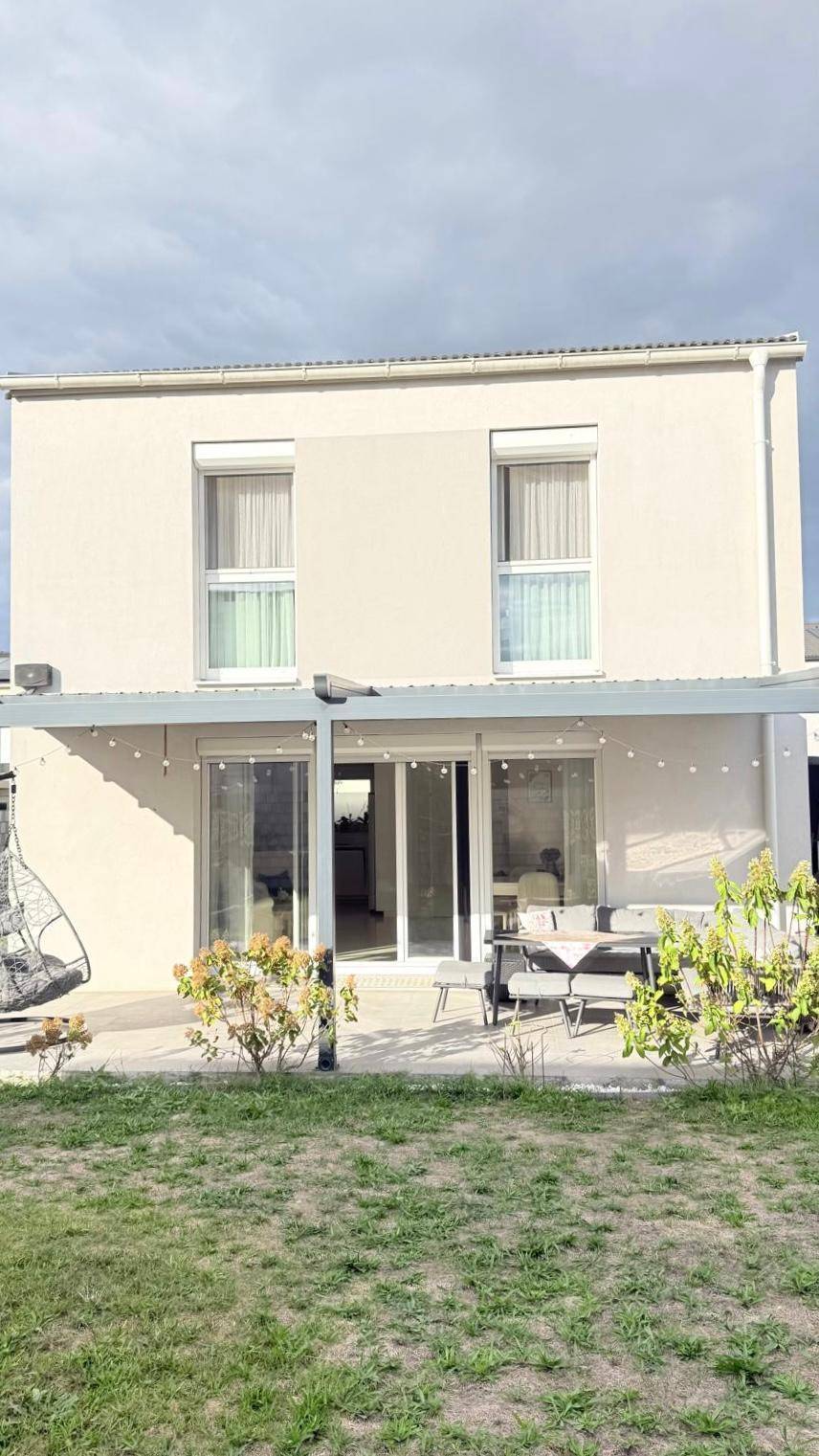 Rückansicht des Hauses mit großer Terrasse, Pergola und einem gepflegten Gartenbereich.