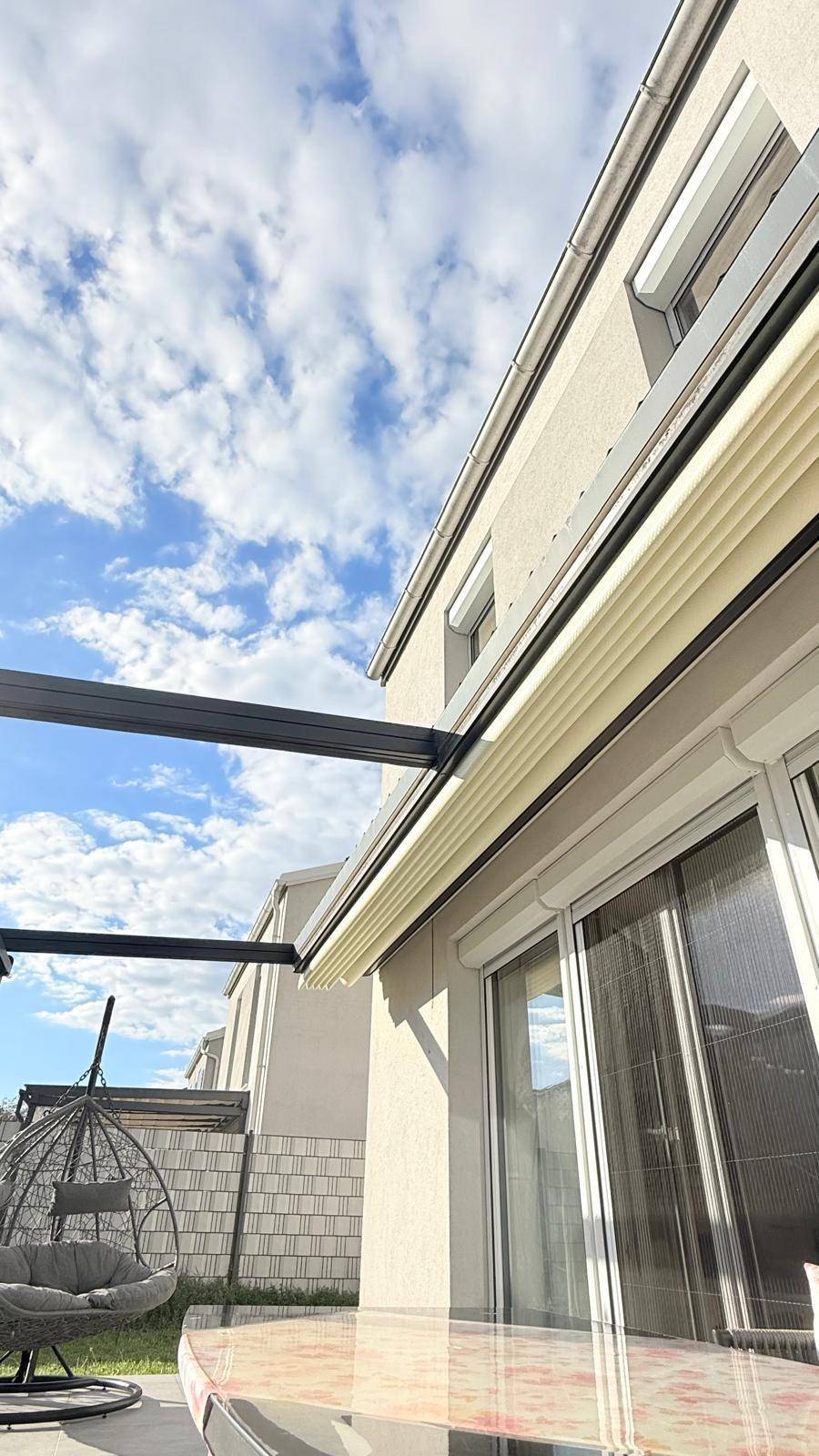 Außenansicht des Hauses mit Fensterrollladen und einem Teil der Terrasse mit Hängesessel.