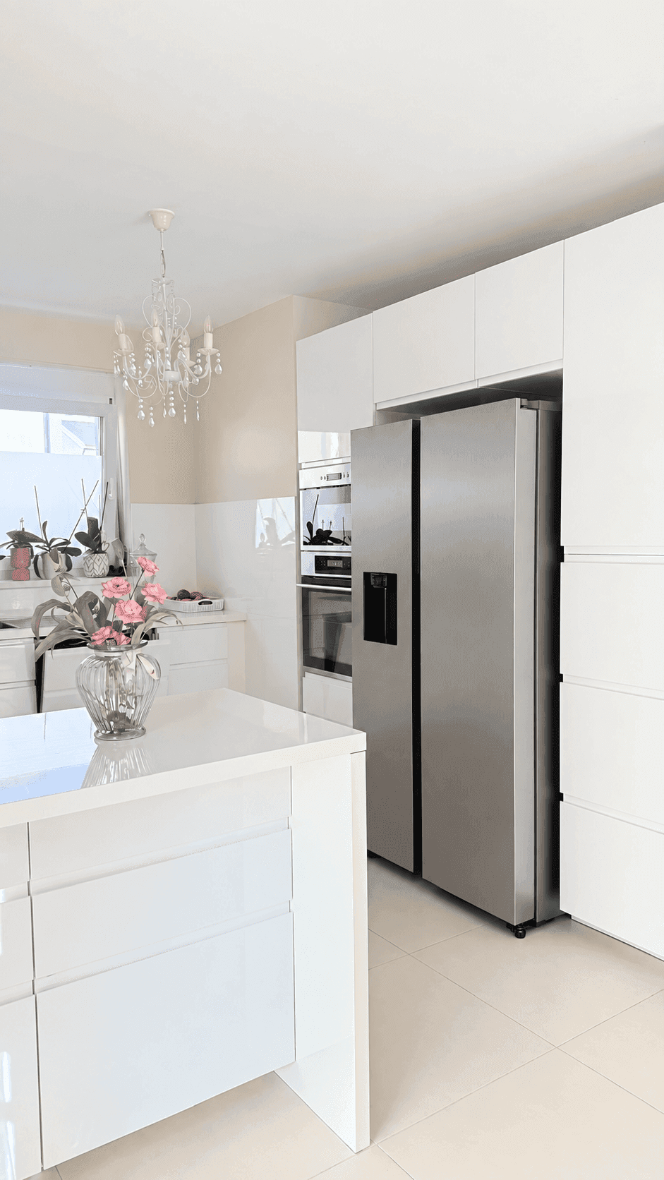 Moderne weiße Küche mit Kochinsel, integrierten Geräten und großem Kühlschrank.