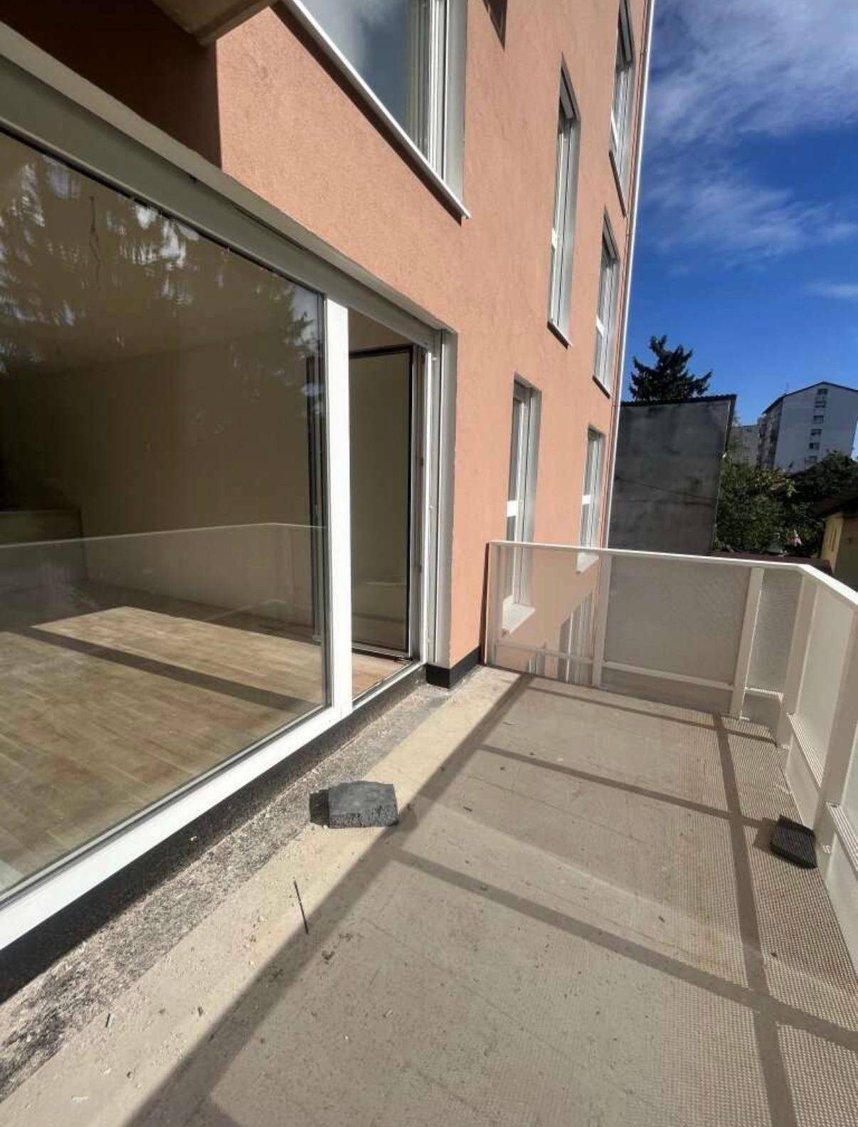 Balkon mit moderner Glasbrüstung und Blick auf die Umgebung, direkt am Gebäude.