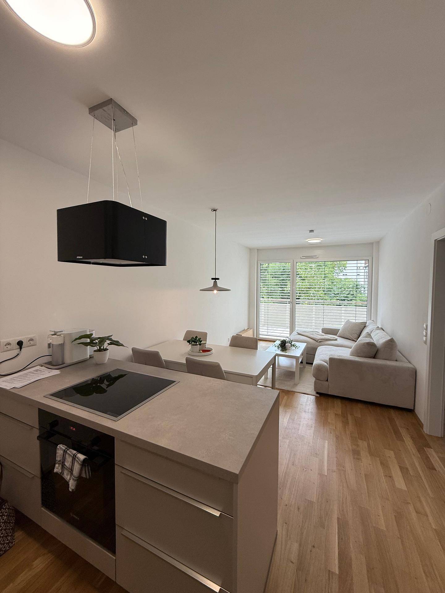 Moderner offener Wohn-Essbereich mit integrierter Küche und Zugang zum Balkon.