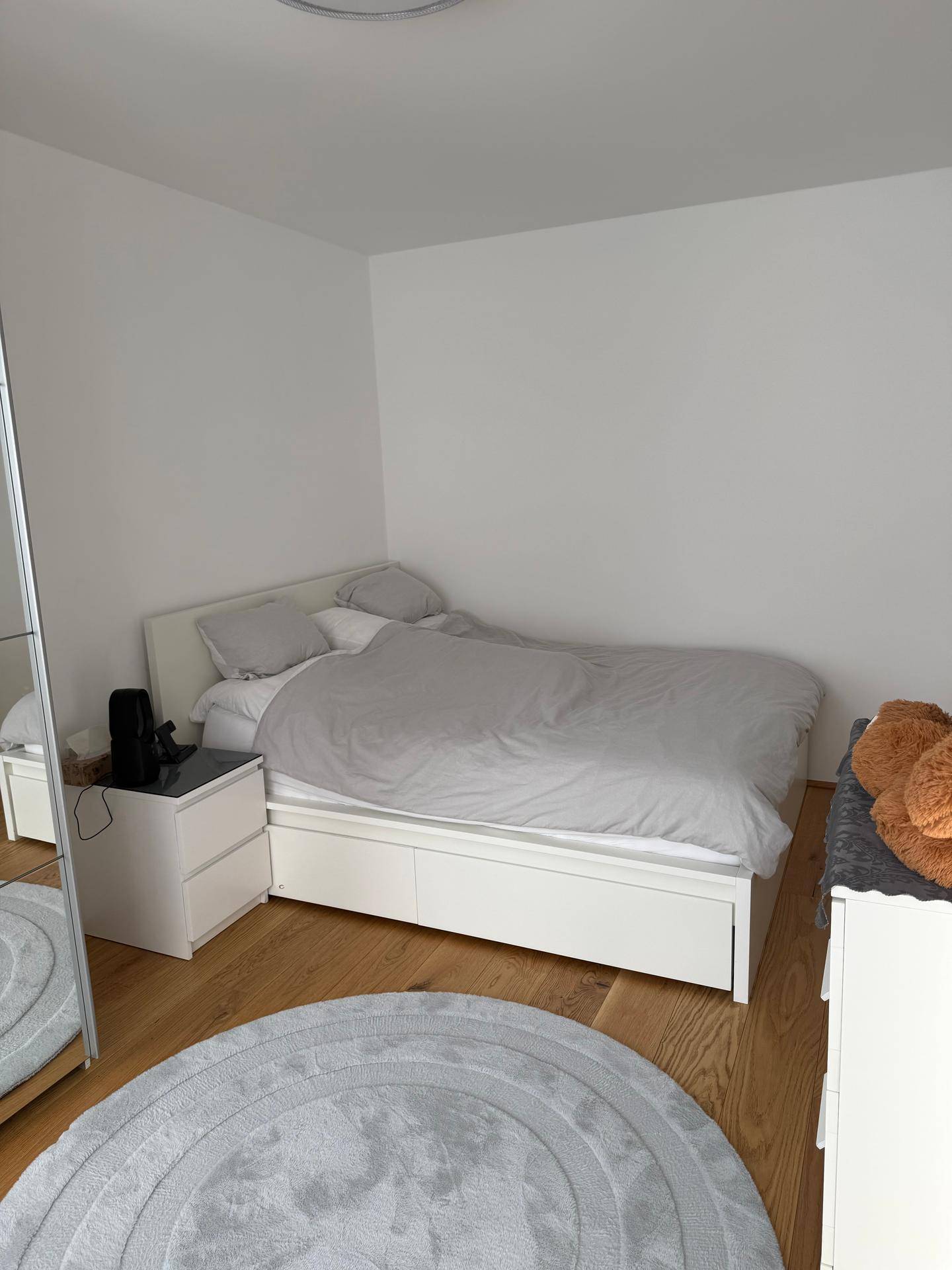 Helles Schlafzimmer mit Holzboden, Doppelbett und Nachttischen in minimalistischem Stil.