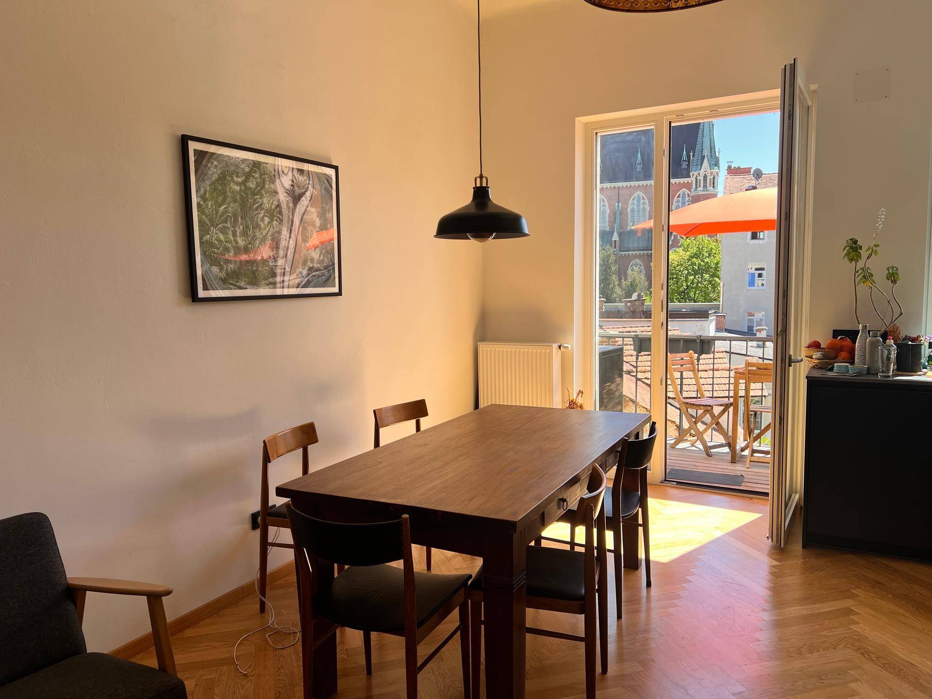 Essbereich mit Holztisch und Stühlen, mit direktem Zugang zu einem sonnigen Balkon.