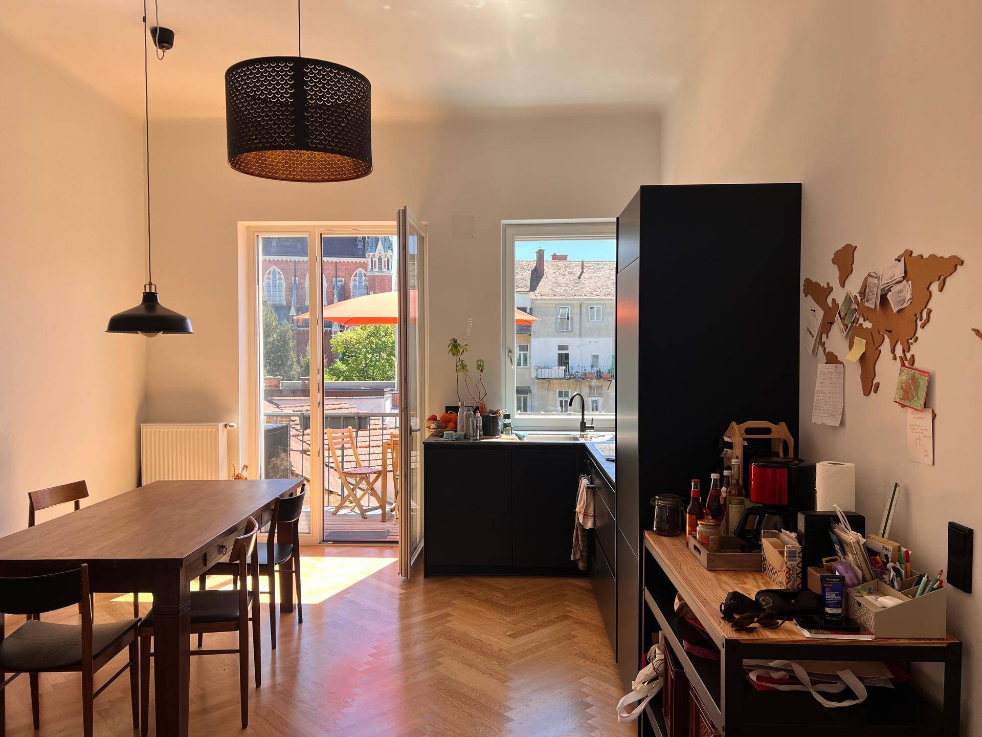 Offener Wohn-Essbereich mit moderner Küche und Zugang zu einem sonnigen Balkon.