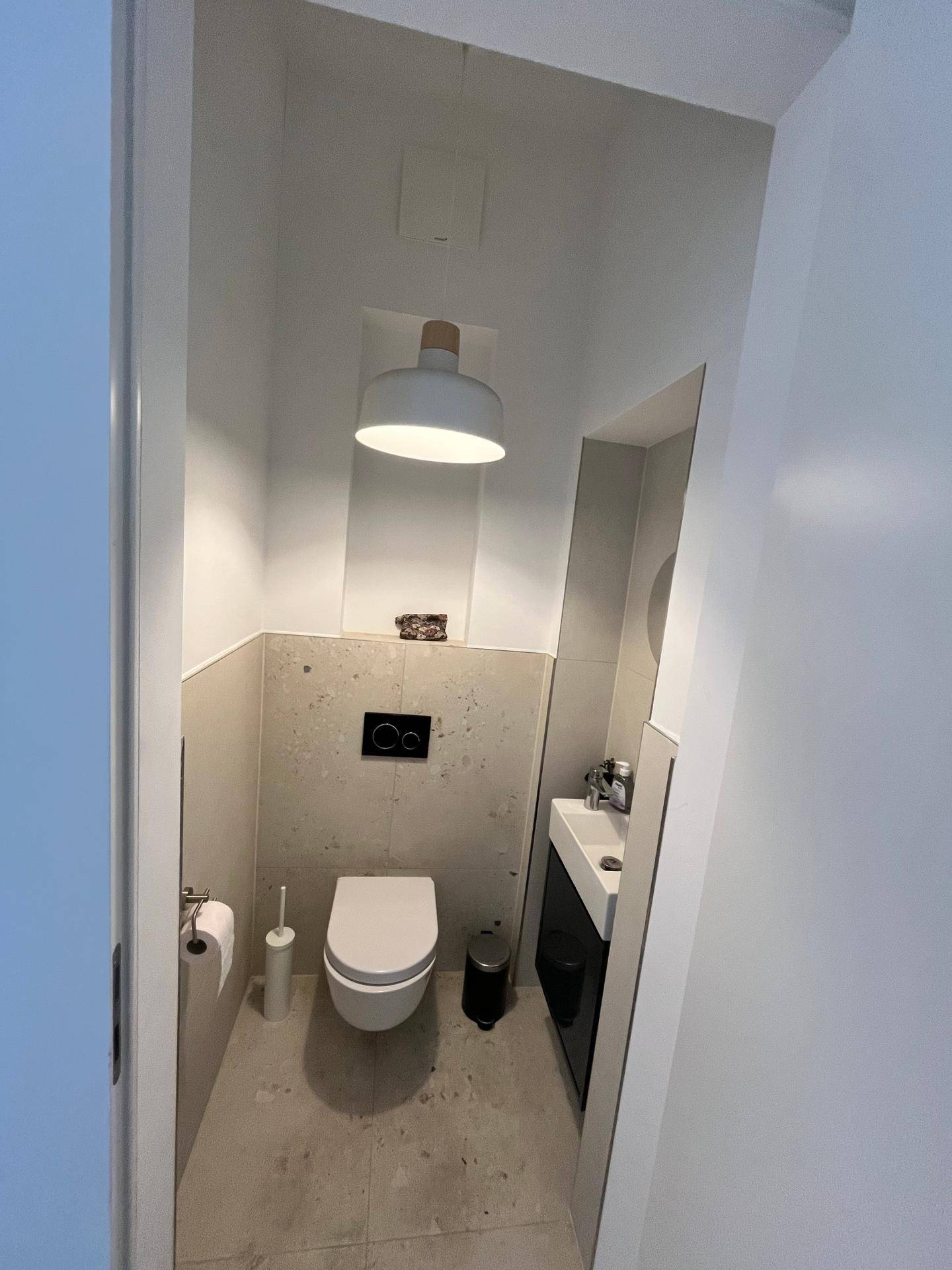 Modernes Gäste-WC mit wandhängender Toilette und kleinem Waschbecken.