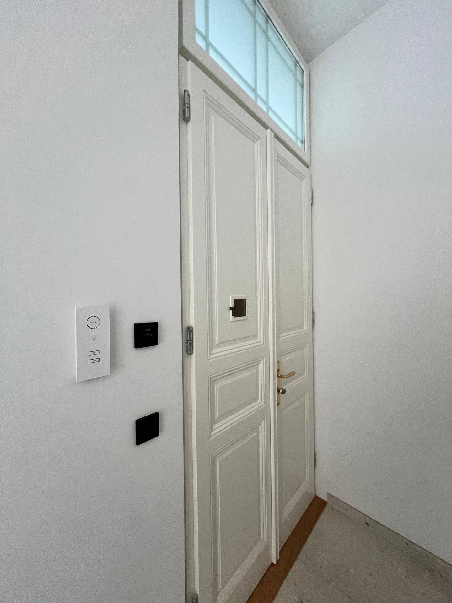 Weiße Doppeltür mit Oberlicht in einem hellen Flur, klassisches Design.