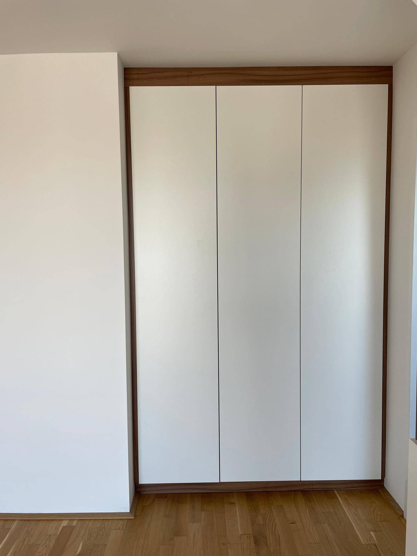 Moderner Einbauschrank mit weißen Türen und Holzrahmen, passend zum hellen Interieur des Raumes.