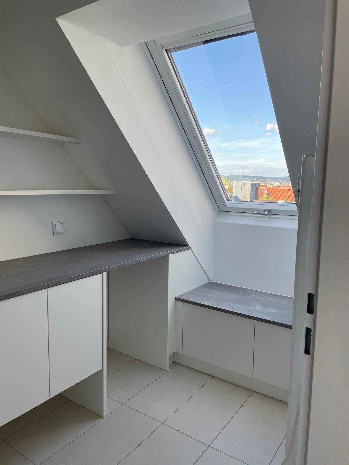 Modernes Badezimmer mit Waschtisch, Ablageflächen und Dachfenster für viel Tageslicht.