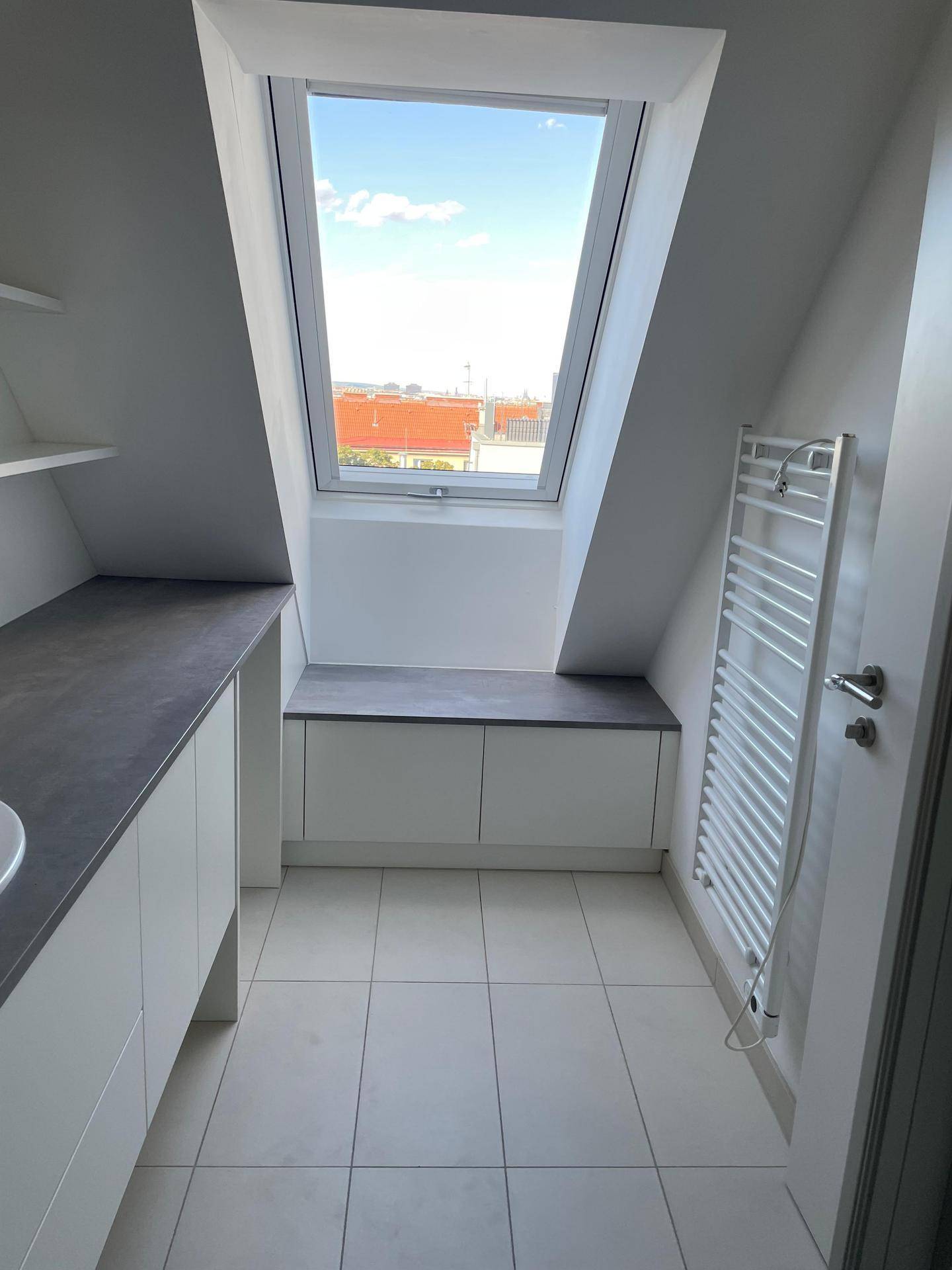 Helles Badezimmer mit Dachfenster, Fliesenboden und beheiztem Handtuchhalter für Komfort.