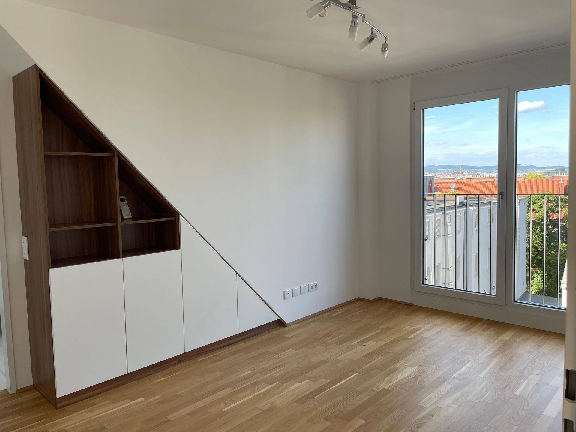 Helles Schlafzimmer mit maßgefertigten Einbauschränken und Blick nach draußen durch den französischen Balkon.